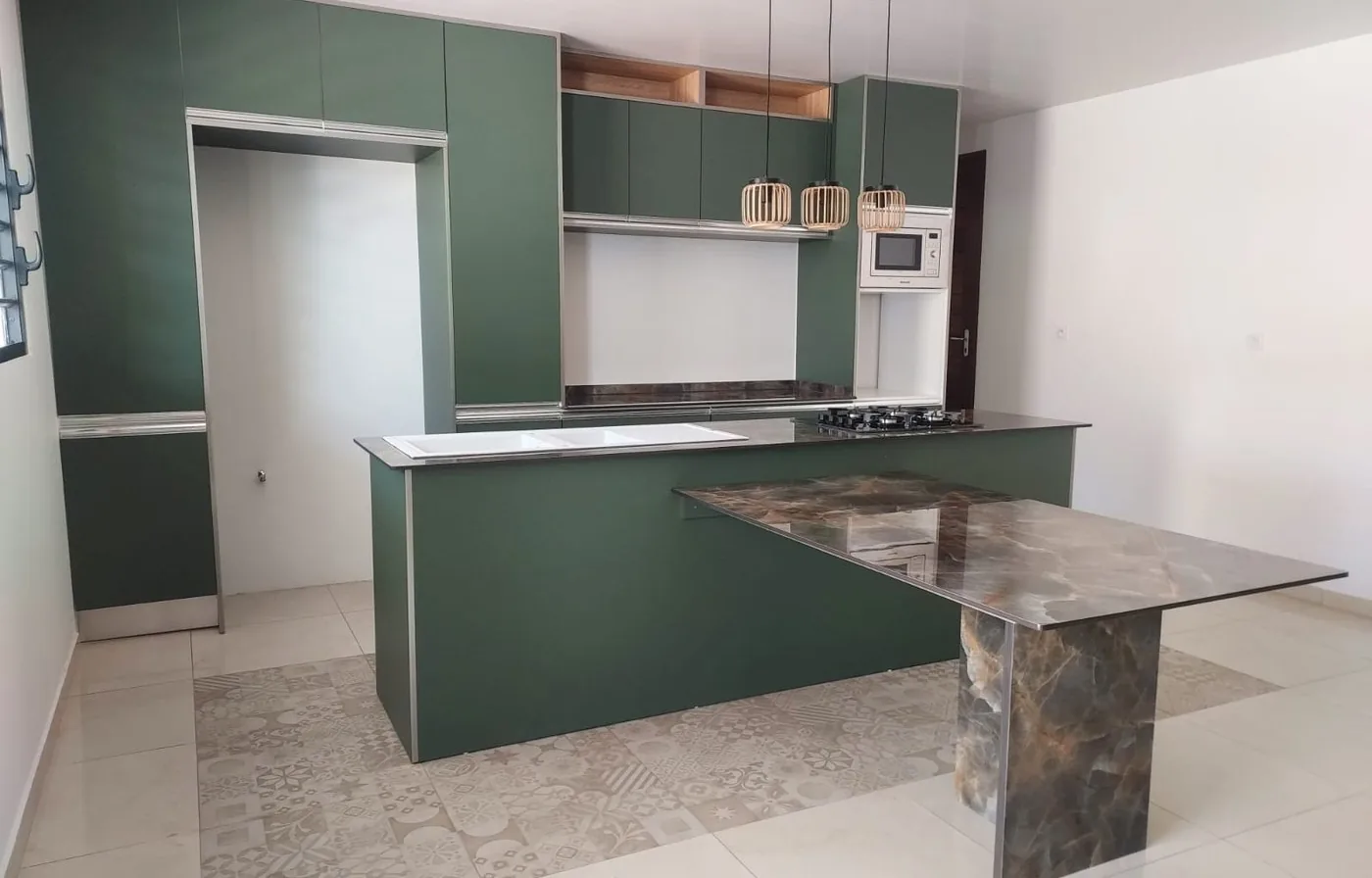 Cuisine vert forêt avec table en céramique onyx et suspensions au-dessus de l'îlot